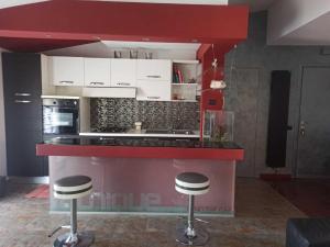 une cuisine avec un comptoir rouge et deux tabourets de bar dans l'établissement Open house, à Campofelice di Roccella