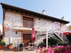 a building with a staircase and a patio with chairs and an umbrella at Apartamentos Turísticos los Abuelos in Montemayor de Pililla