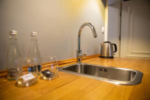 a kitchen sink with bottles and glasses on a counter at Apartamenty Pod Zegarem in Mikołajki