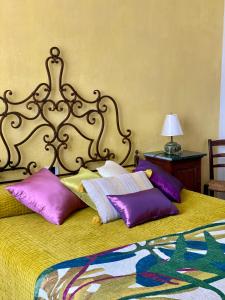 1 dormitorio con 1 cama con almohadas moradas en villa porta a colle, en Castiglione della Pescaia