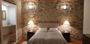 1 dormitorio con pared de piedra, 1 cama y 2 lámparas en B&B Casa Fossello, en Montabone