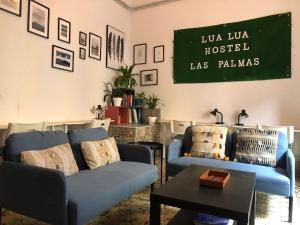 a living room with blue couches and a chalkboard on the wall at Lua Lua Hostel Las Palmas in Las Palmas de Gran Canaria