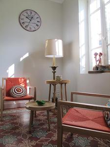 sala de estar con silla y reloj en la pared en La Cour Des Sens en Lagnes