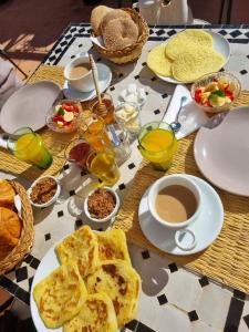 a table topped with plates of food and cups of coffee at Riad Full Moon in Marrakesh