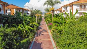 a pathway in a garden with palm trees and houses at Eftalia Holiday Village in Konaklı