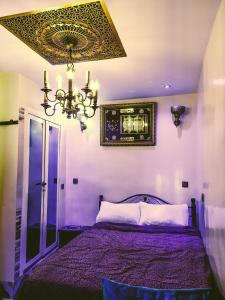 a bedroom with a purple bed with a chandelier at Dar Rihanne in Fez