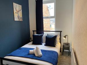 1 cama con almohadas azules y blancas y ventana en Rawling - Canny 2 bed flat close to Ncle free wifi & parking en Gateshead