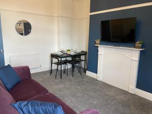a living room with a couch and a table with a television at Rawling - Canny 2 bed flat close to Ncle free wifi & parking in Gateshead
