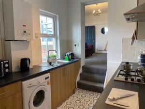 a kitchen with a washing machine and a staircase at Rawling - Canny 2 bed flat close to Ncle free wifi & parking in Gateshead