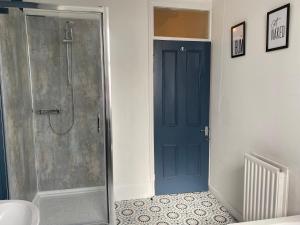 a bathroom with a shower and a blue door at Rawling - Canny 2 bed flat close to Ncle free wifi & parking in Gateshead +8 photos