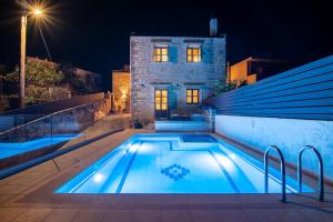 une piscine devant une maison la nuit dans l'établissement Alexandros Villa, à Skouloúfia