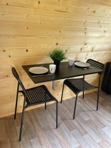 uma mesa preta com duas cadeiras e uma mesa e dois pratos em Tiny rooms @ camping val d'Or em Enscherange