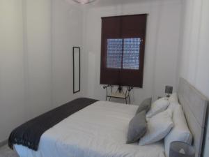 a white bedroom with a bed and a window at CASA TITO JOSE in Valle de Abdalagís