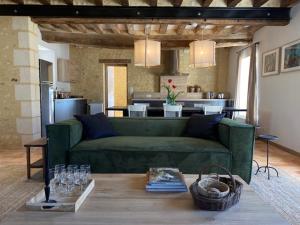 sala de estar con sofá verde y cocina en Chambres d'hôtes du Bistrot des écuries en Cour-Maugis-sur-Huisne