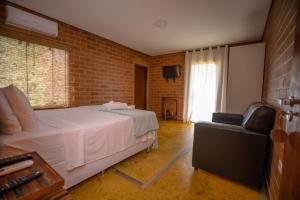 um quarto com uma cama branca e uma cadeira em Woodstock guesthouse em Alto Paraíso de Goiás