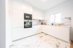 una cocina blanca con armarios y electrodomésticos blancos en Apartamento situado no centro histórico da cidade, en Setúbal