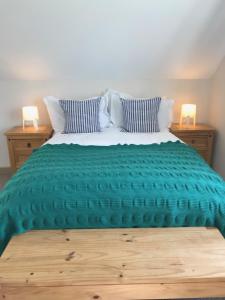 a bed with a green comforter on top of it at Harvest Moon-ROOMS ONLY in Doolin