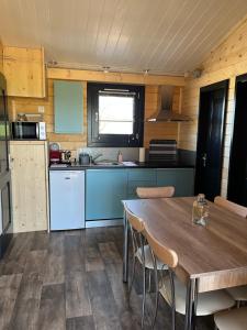 eine Küche mit einem Holztisch mit Stühlen und einem Tisch in der Unterkunft Chalet avec spa, Au Bois Quartois in La Quarte