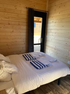 Bett in einem Holzzimmer mit Handtüchern darauf in der Unterkunft Chalet avec spa, Au Bois Quartois in La Quarte