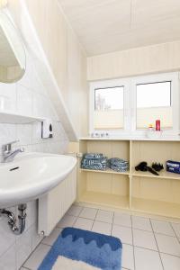 ein Badezimmer mit einem Waschbecken und zwei Fenstern in der Unterkunft haus-sand-am-meer in Neuharlingersiel