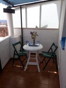 une table blanche avec deux chaises et un vase de fleurs dans l'établissement Piso De La Ermita, à Mijas