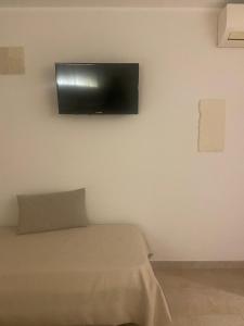 TV de pantalla plana colgada en una pared blanca en Dimora di Tours en Fasano