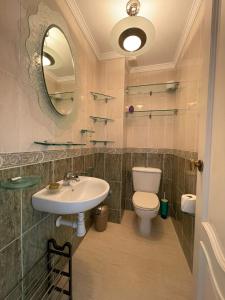 La salle de bains est pourvue d'un lavabo, de toilettes et d'un miroir. dans l'établissement Aires de Regla, Apartamentos Living Sur, à Chipiona