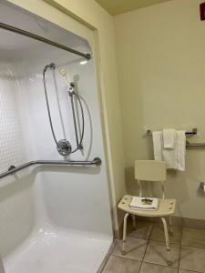 ein Bad mit einer Badewanne und einer Dusche mit einem Stuhl in der Unterkunft Howard Johnson by Wyndham Clarksville Tennessee in Clarksville
