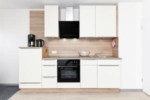 a kitchen with white cabinets and a sink at haus-sand-am-meer in Neuharlingersiel