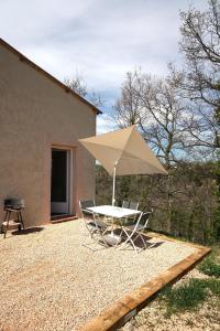 a table and chairs with an umbrella and a grill at Studio Indépendant Douceur Provençale in Montagnac