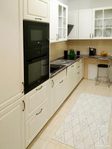 a kitchen with white cabinets and a black appliance at Staromiejska Apartamenty in Sandomierz