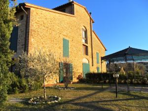 een groot bakstenen gebouw met groene luiken erop bij Casa Leonardo, Montaione, Mura in Montaione
