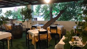 un ristorante con tavoli, sedie e un albero di Cinquestelle Albergo del centro storico a Palinuro