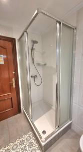 a bathroom with a shower stall and a glass door at Pension Angelines, Sneuu Hostel Santander in Santander