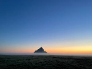 un amanecer nebuloso con un castillo en el horizonte en Les2 cerisiers en Pontorson