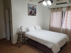 1 dormitorio con cama, taburete y una foto en la pared en Paradise Found en La Ceiba