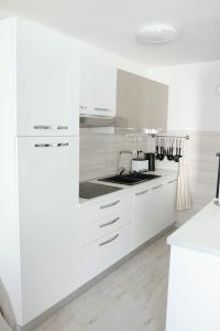 La cuisine est équipée de placards blancs et d'un four avec plaques de cuisson. dans l'établissement Apartment Glavarić, à Omiš