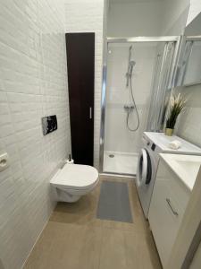 a white bathroom with a toilet and a shower at Wiejska 14 - 500m od Sejmu Rzeczypospolitej - 450m do Ambasady USA - Smart TV - WiFi - w pełni wyposażona kuchnia in Warsaw