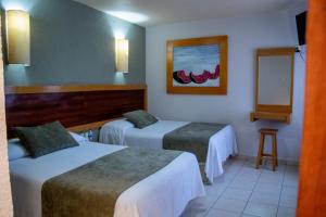 a hotel room with two beds and a mirror at Hotel Qualitel Centro Histórico in Morelia