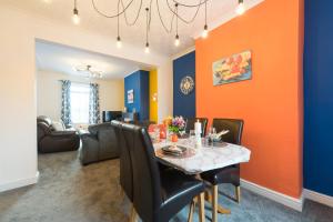 uma sala de jantar com uma parede laranja e azul em Adom Home Away From Home 4 Beds- 5 Mins to Hull Stadium em Hull
