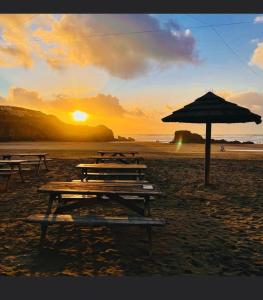eine Gruppe Picknicktische am Strand mit Sonnenschirm in der Unterkunft new Perran holiday resort in Newquay