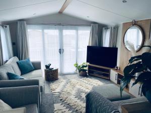 uma sala de estar com um sofá e uma televisão em new Perran holiday resort em Newquay