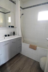a white bathroom with a sink and a tub at Maison au cœur du bourg de Creully - 8km de la mer in Creully