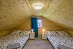2 łóżka w drewnianym pokoju z niebieskimi zasłonami w obiekcie Domki Piamola Kąty Rybackie w Kątach Rybackich