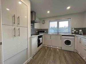 una cucina con armadi bianchi e una lavatrice/asciugatrice di Modern 2 Bed Apartment a Oban