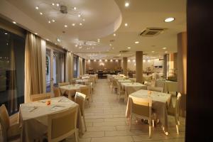 una sala da pranzo con tavoli e sedie bianchi di Hotel Europa a Desenzano del Garda