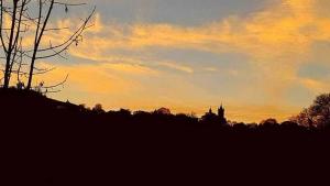 einen Sonnenuntergang mit einem Uhrturm in der Ferne in der Unterkunft Turismo Rural La Tablá in Alles