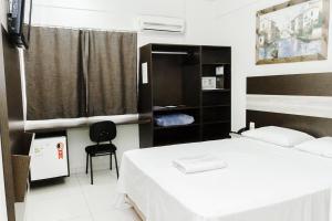 1 dormitorio con 1 cama y 1 silla en La Vitre Hotel, en Jataí