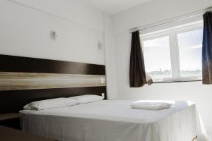 a bedroom with a white bed with a window at La Vitre Hotel in Jataí