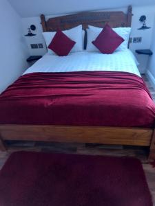 a bedroom with a large bed with red and white pillows at Derrywilligan Guest Accommodation in Bessbrook